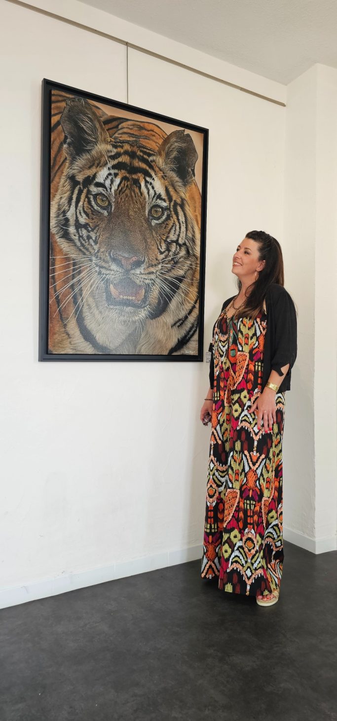 Femme en robe colorée devant un portrait de tigre sur un mur.
