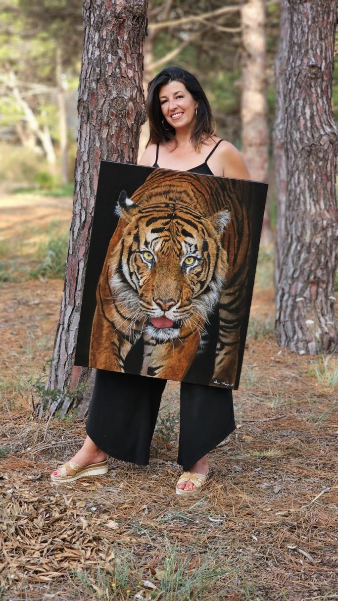 Femme portant une grande toile d'un tigre, se tenant dans une forêt.